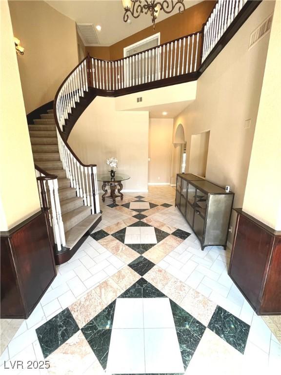 8690 W Ford Ave, Las Vegas, NV 89148 - entryway with arched walkways, inlaid floor details, stairway, a towering ceiling, and a chandelier