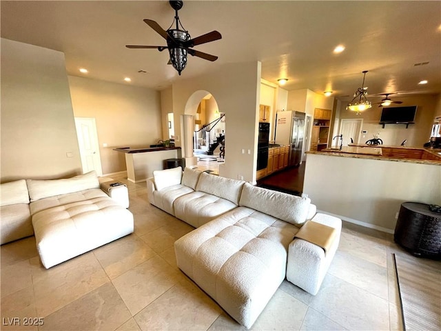8690 W Ford Ave, Las Vegas, NV 89148 - tiled living room featuring ceiling fan, arched walkways, recessed lighting, baseboards, and stairs
