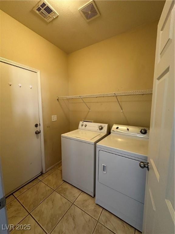 washroom with washer and dryer, laundry area, light tile patterned floors, and visible vents