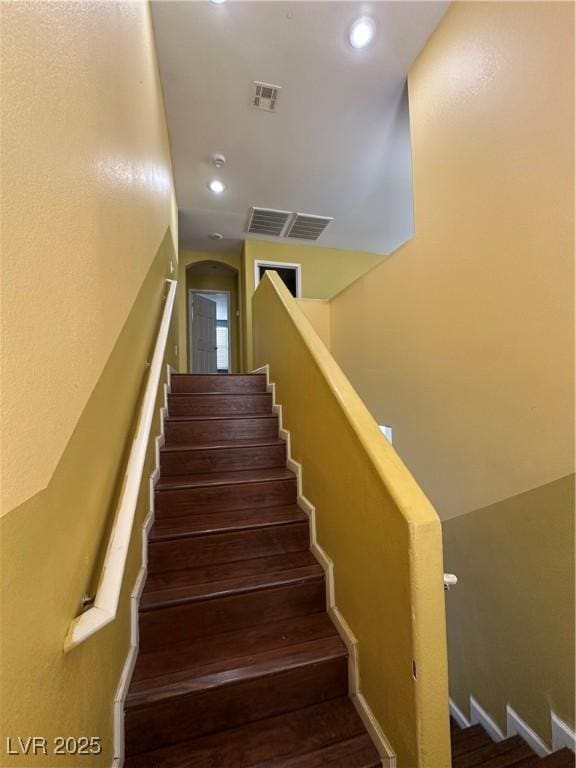 staircase featuring wood finished floors, visible vents, and recessed lighting
