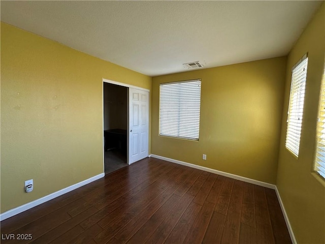 unfurnished room with dark wood-type flooring, baseboards, and visible vents