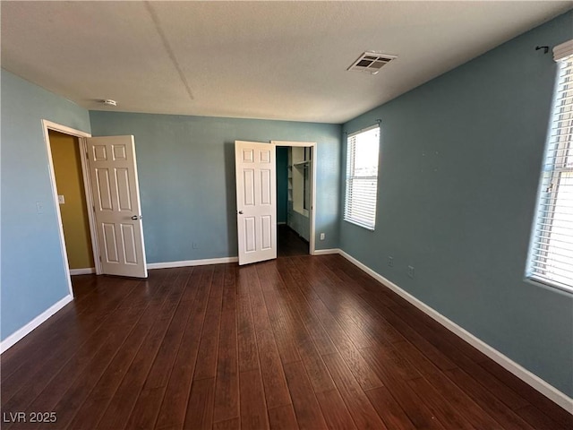 spare room featuring baseboards, dark wood-style floors, and visible vents
