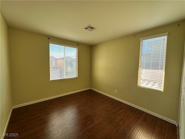 empty room with visible vents, baseboards, and dark wood-style floors