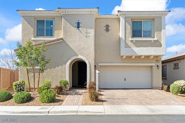view of front of house with stucco siding, an attached garage, decorative driveway, and fence