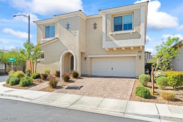 view of front of home with stucco siding, an attached garage, and decorative driveway