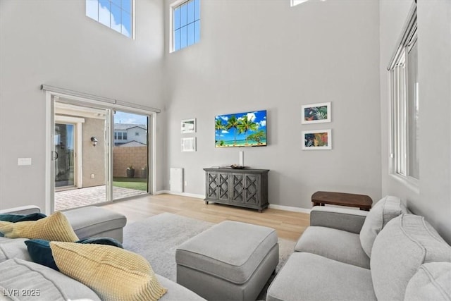 living area featuring a high ceiling, wood finished floors, and baseboards