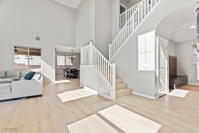 living area featuring wood finished floors, baseboards, stairs, a high ceiling, and arched walkways