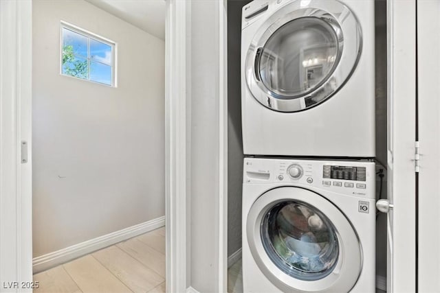 laundry room featuring stacked washer / dryer and baseboards