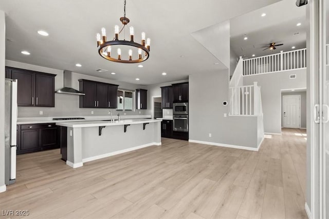 3062 Echoed Rondel Ln, Henderson, NV 89044 - kitchen with appliances with stainless steel finishes, wall chimney range hood, a chandelier, light countertops, and a kitchen breakfast bar
