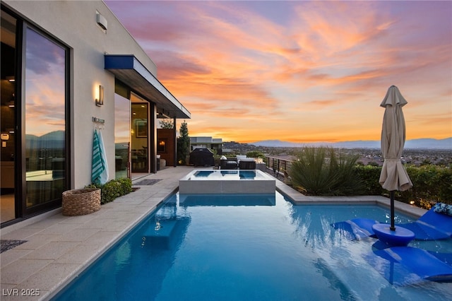 387 Solitude Peak Ln, Henderson, NV 89012 - pool at dusk with a patio, an outdoor pool, a mountain view, and an in ground hot tub