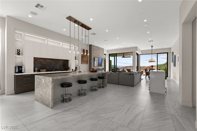 387 Solitude Peak Ln, Henderson, NV 89012 - kitchen featuring open floor plan, modern cabinets, a kitchen bar, white cabinets, and decorative light fixtures