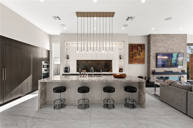 387 Solitude Peak Ln, Henderson, NV 89012 - kitchen featuring a breakfast bar area, visible vents, modern cabinets, and marble finish floor