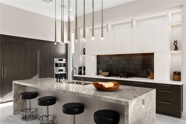 387 Solitude Peak Ln, Henderson, NV 89012 - kitchen featuring a breakfast bar area, stainless steel double oven, a sink, and modern cabinets