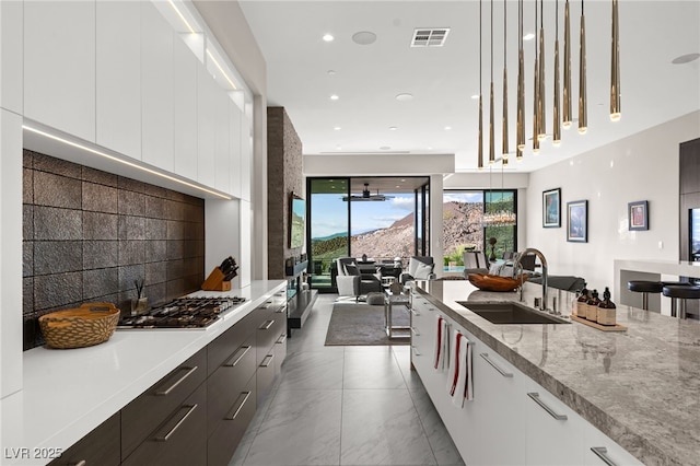387 Solitude Peak Ln, Henderson, NV 89012 - kitchen featuring white cabinets, stainless steel gas stovetop, a sink, and modern cabinets