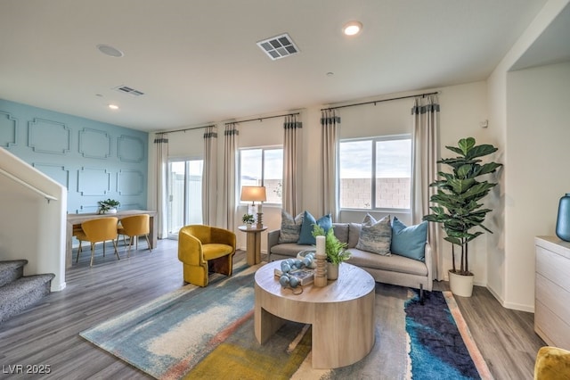 living area with wood finished floors, visible vents, and a wealth of natural light