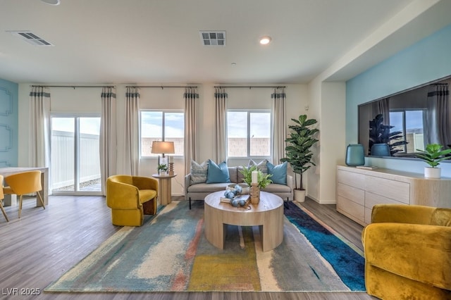 living room with recessed lighting, visible vents, and wood finished floors