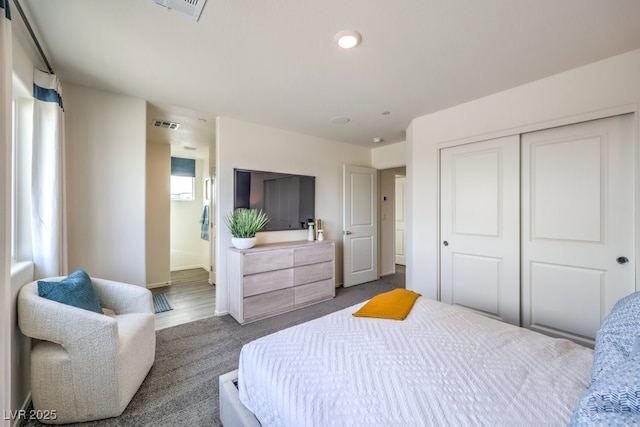 bedroom featuring dark carpet, visible vents, a closet, and connected bathroom