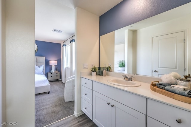 bathroom with wood finished floors, vanity, ensuite bathroom, and visible vents