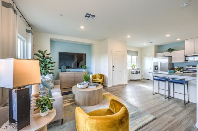 living area with recessed lighting, visible vents, and light wood-style flooring