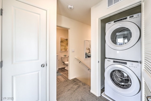 laundry area with carpet, visible vents, laundry area, and stacked washer and clothes dryer