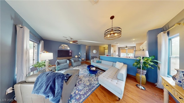 living room with ceiling fan with notable chandelier and wood finished floors