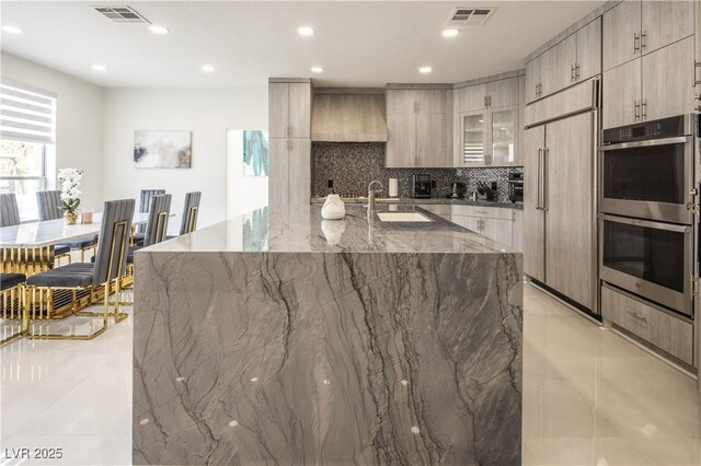 kitchen with paneled built in fridge, modern cabinets, stainless steel double oven, a sink, and recessed lighting