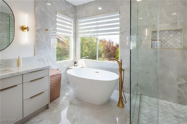 full bath featuring a stall shower, marble tiled flooring, a freestanding bath, vanity, and tile walls