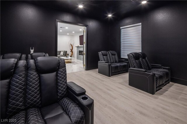 home theater featuring wood finished floors, recessed lighting, and a textured wall