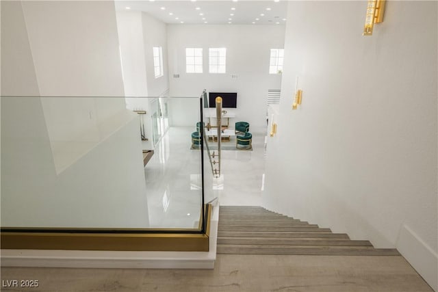stairway with a towering ceiling and recessed lighting