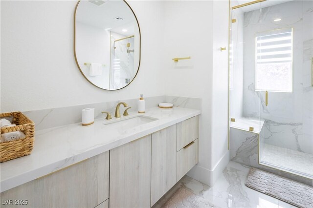 bathroom featuring marble tiled floors, a marble finish shower, and vanity