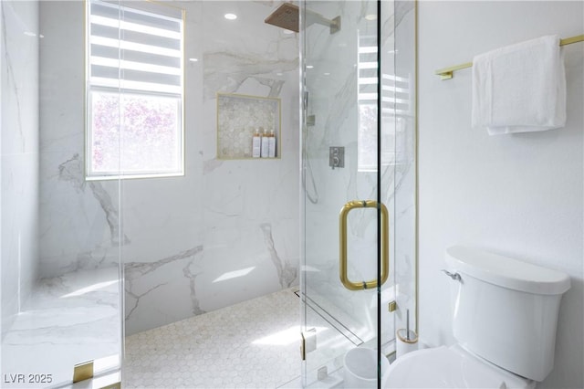 bathroom featuring a marble finish shower and toilet