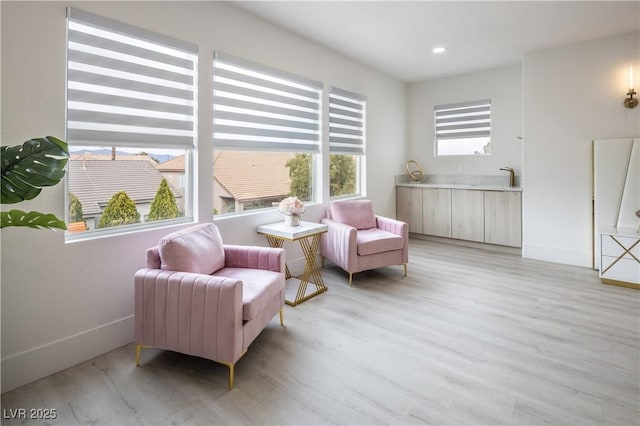 living area featuring light wood finished floors, baseboards, and recessed lighting
