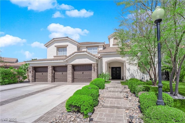mediterranean / spanish-style house with french doors, stucco siding, concrete driveway, an attached garage, and stone siding