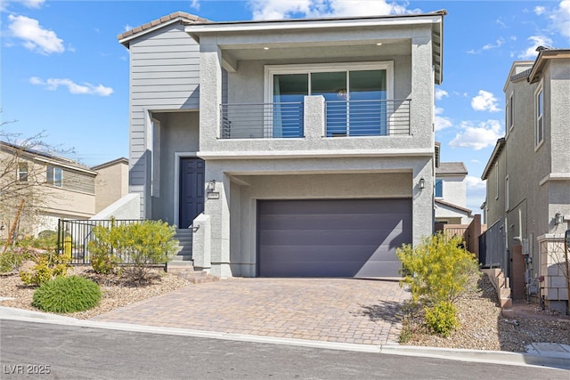 view of front of house featuring a garage, a balcony, decorative driveway, and stucco siding