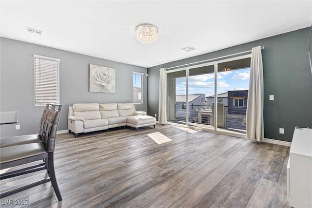 unfurnished living room with visible vents, baseboards, and wood finished floors