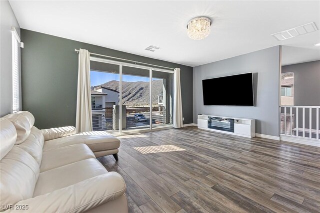 living room featuring wood finished floors, baseboards, and visible vents