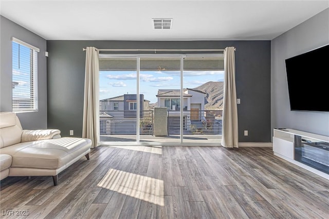 living area with wood finished floors, baseboards, and visible vents