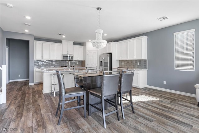 kitchen featuring white cabinetry, baseboards, appliances with stainless steel finishes, and a notable chandelier