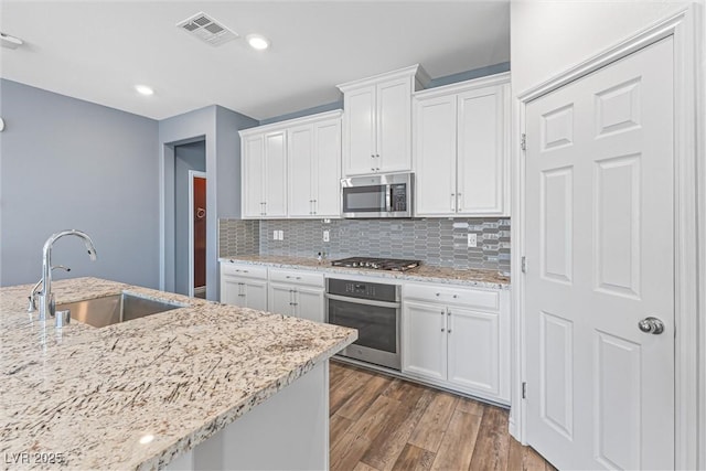 kitchen featuring white cabinets, visible vents, appliances with stainless steel finishes, wood finished floors, and a sink