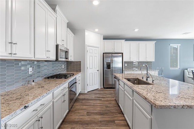 kitchen featuring appliances with stainless steel finishes, a sink, dark wood-style floors, and white cabinets