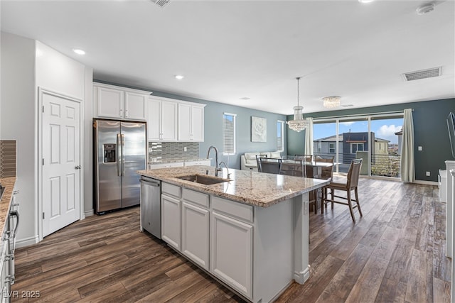 kitchen with white cabinetry, visible vents, a center island with sink, stainless steel appliances, and a sink
