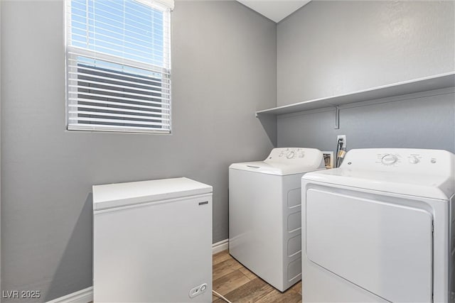 clothes washing area featuring laundry area, separate washer and dryer, light wood-style floors, and baseboards