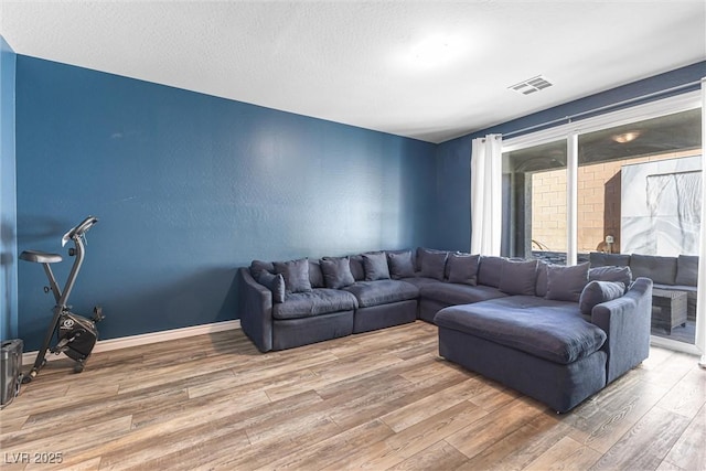 living area with wood finished floors, baseboards, and visible vents