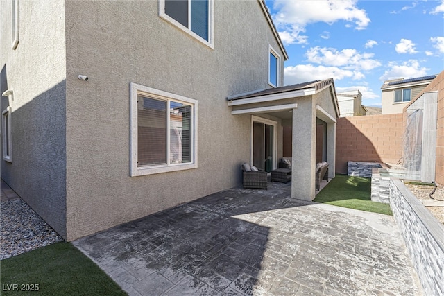 rear view of property featuring a fenced backyard, outdoor lounge area, a patio, and stucco siding