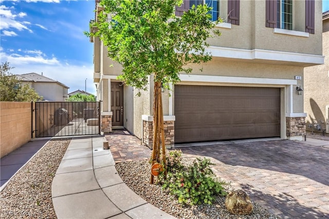 415 Carsin Wayne Ct, North Las Vegas, NV 89031 - view of front of house featuring stucco siding, stone siding, an attached garage, and a gate