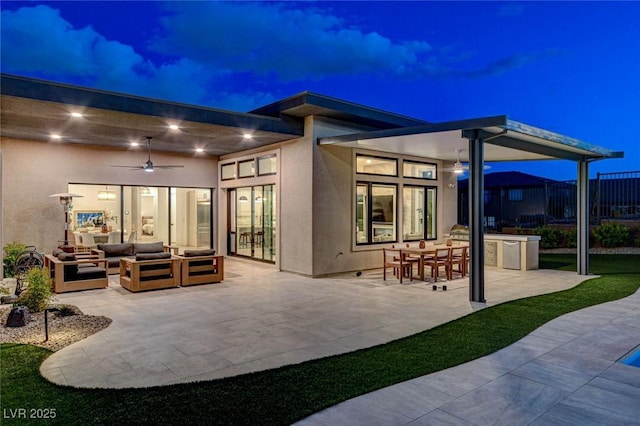 12199 Canyon Sunset St, Las Vegas, NV 89138 - back of house at night featuring an outdoor living space, ceiling fan, stucco siding, a patio area, and fence