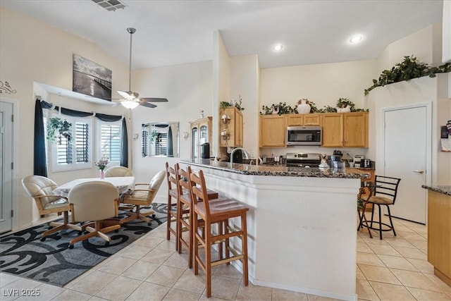 1066 Vanlier Ln, Henderson, NV 89015 - kitchen featuring appliances with stainless steel finishes, light tile patterned flooring, a kitchen breakfast bar, a peninsula, and a high ceiling