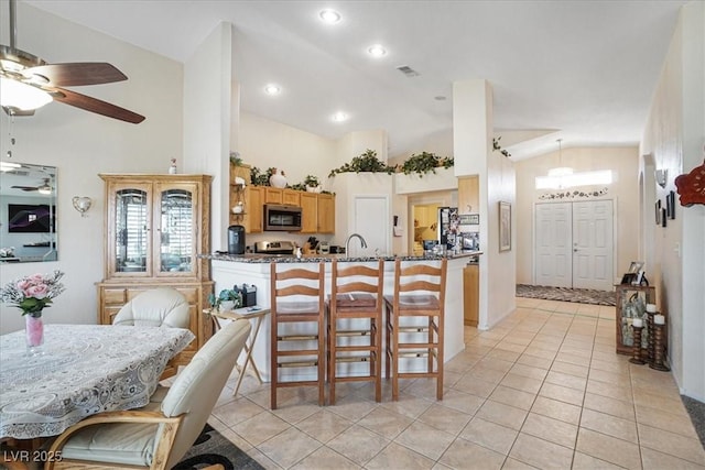 1066 Vanlier Ln, Henderson, NV 89015 - kitchen with stainless steel microwave, lofted ceiling, plenty of natural light, light tile patterned floors, and a ceiling fan