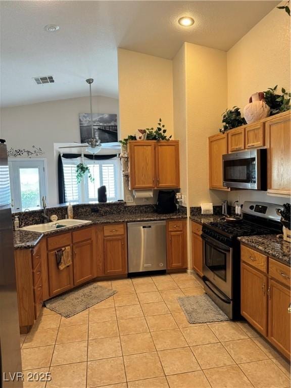 1066 Vanlier Ln, Henderson, NV 89015 - kitchen featuring appliances with stainless steel finishes, a sink, brown cabinetry, light tile patterned flooring, and lofted ceiling