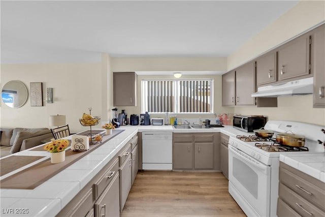 5530 Berchmans Ave, Las Vegas, NV 89122 - kitchen featuring tile counters, white appliances, light wood-type flooring, gray cabinets, and under cabinet range hood